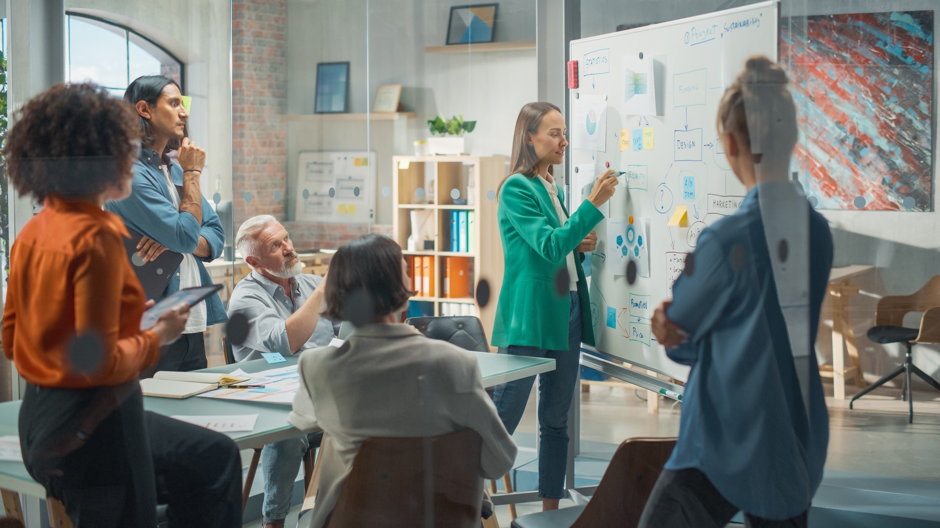 Modern Creative Agency Meeting: Confident Black Female Engineer Uses Whiteboard, Makes Report to a Group of Engineers, Managers Talks, and Shows Statistics, Growth and Analysis Information